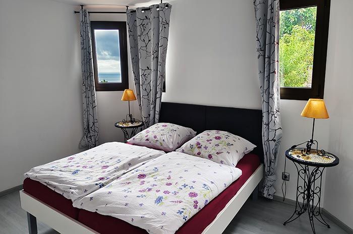 Schlafzimmer mit großem Eisenbett und Meerblick in der Villa Faisan auf Teneriffa